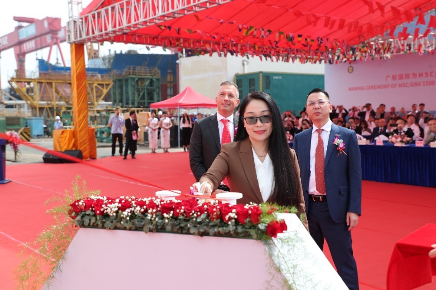 A group of people standing in front of a red carpet Description automatically generated